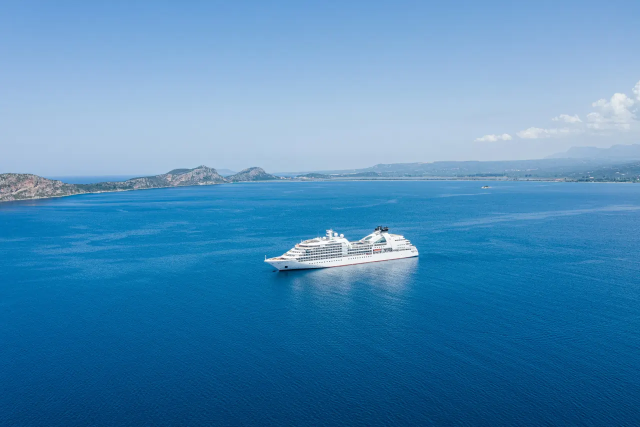 A small cruise ship anchored off a Mediterranean coast