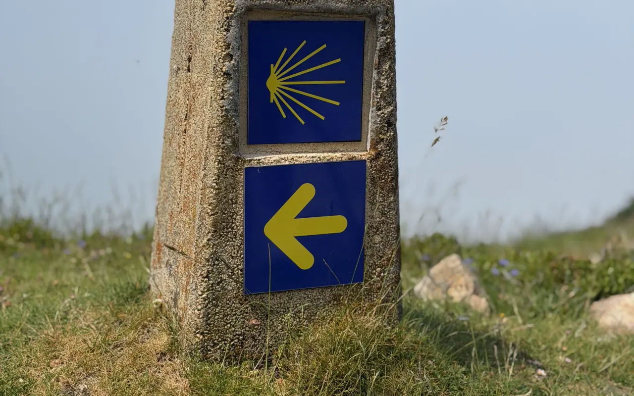 A Camino waymarker with the yellow scallop shell and arrow